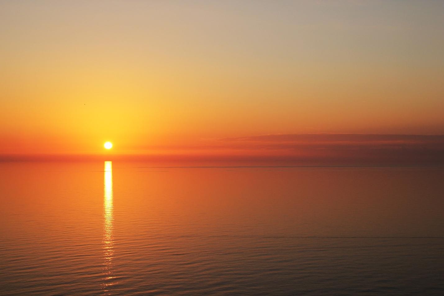 A sunset over a body of water Description automatically generated